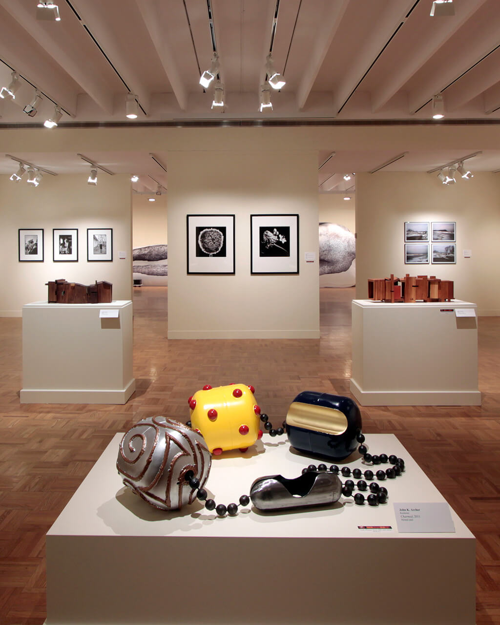 A pedestal with ceramics work in a large gallery space; on the white walls hang more works of art