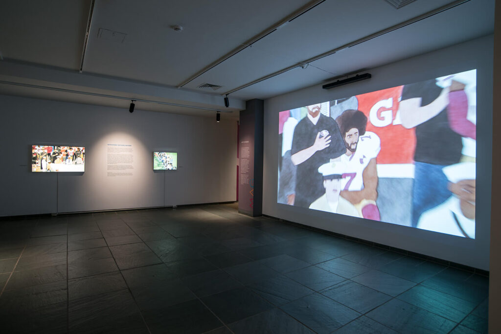 MAG's Forman Gallery with artwork projected on one wall and two lightboxes installed on another wall.