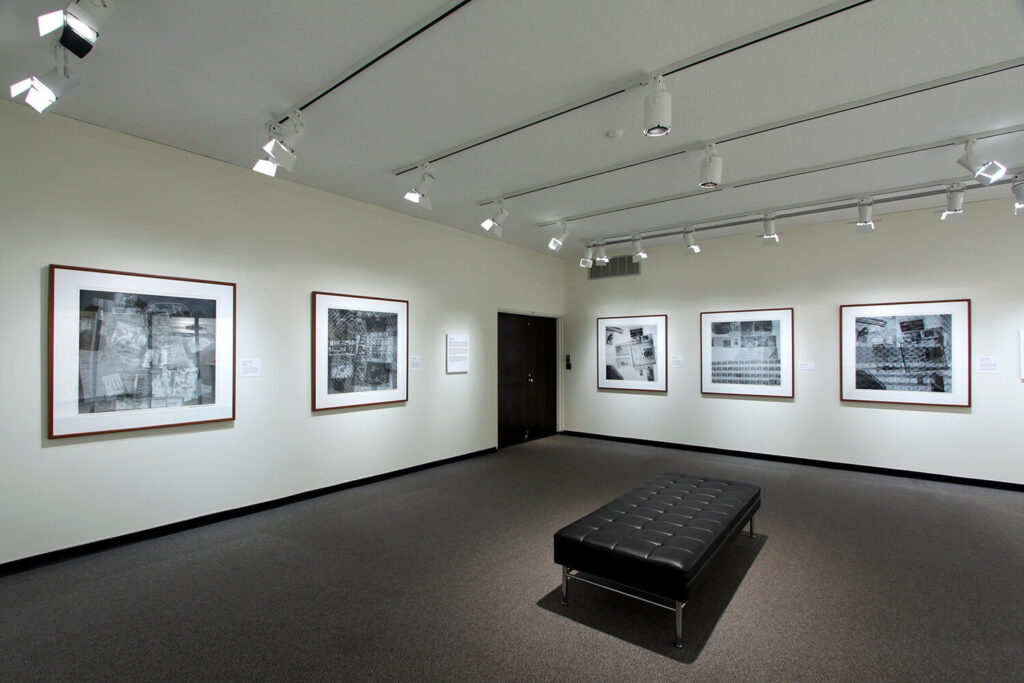 Framed works of print and collage art by Robert Rauschenberg on white walls in a small gallery.
