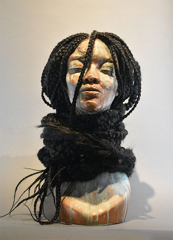 Sculpture of a human head with long, braided hair wrapped around their neck