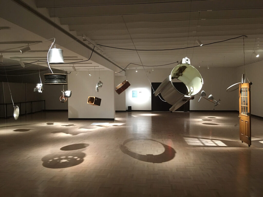Many different kinds of objects suspended in place in a wide open room.