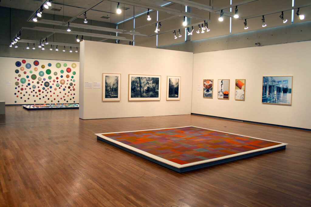 Works of art that relate to producing multiple copies of a single work of art, on the floor and white walls of a gallery.