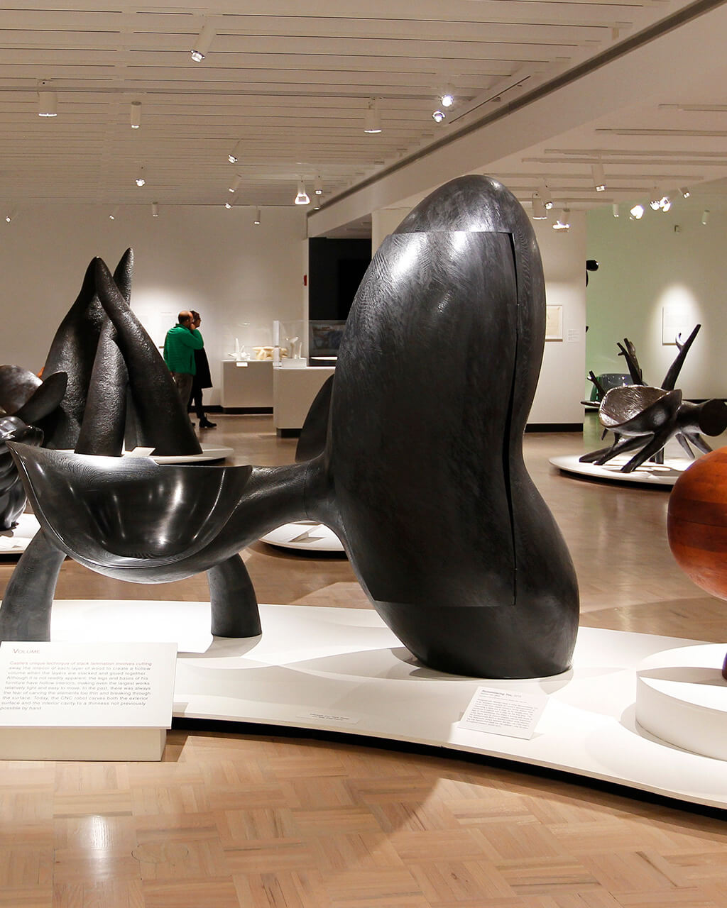 Organically-shaped wooden furniture sculptures by Wendell Castle on view in a large, white-walled gallery.