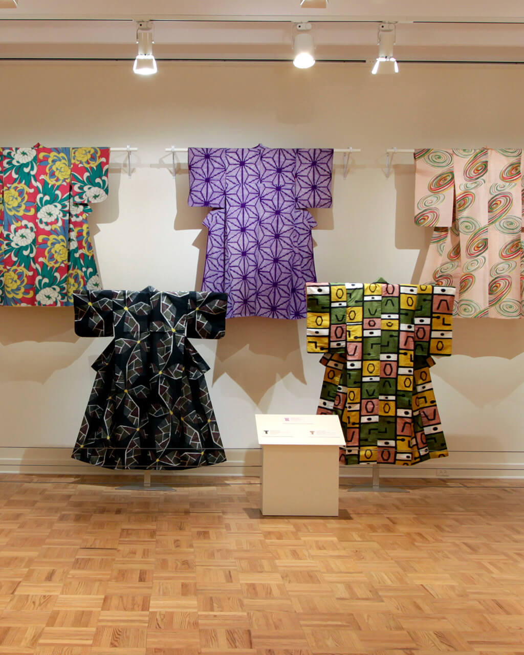 Kimono hung for display in a white-walled gallery space.