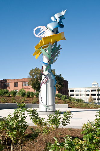 Sculptural steel statue with colorful ribbons stretching into the air