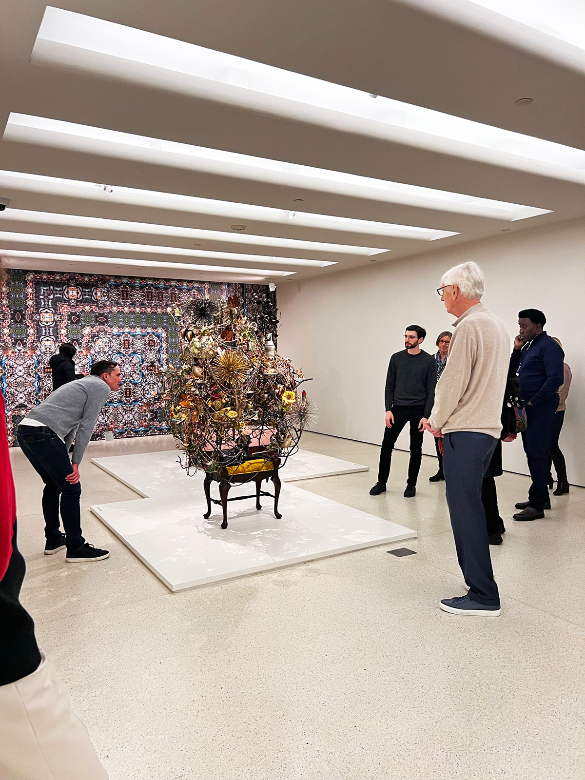 Various people standing around an abstract metallic sculpture