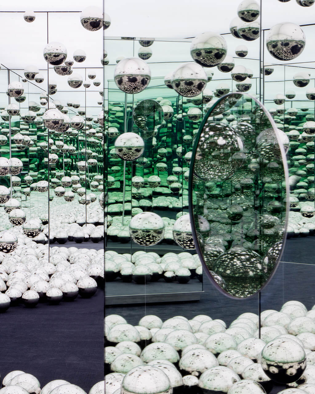 Interior of a mirrored room with silver metal balls on the floor