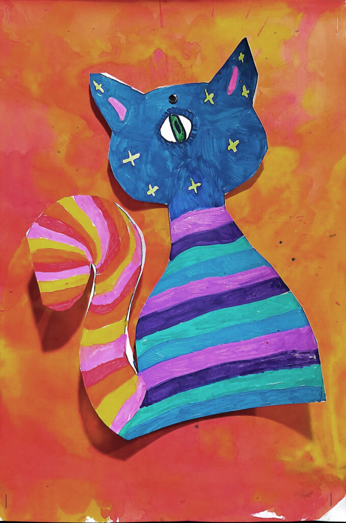 A paper cut-out in the shape of a cat colored with blue, teal, and purple stripes
