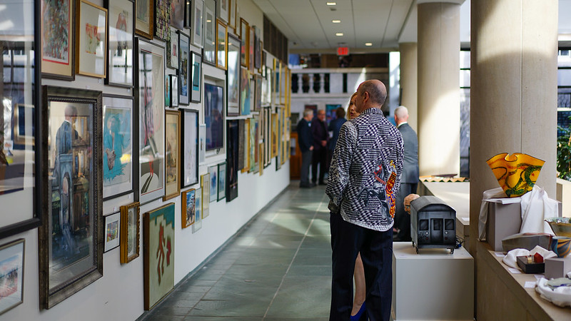 A person looking at framed works of art hung on the walls of the Vanden Brul Pavilion