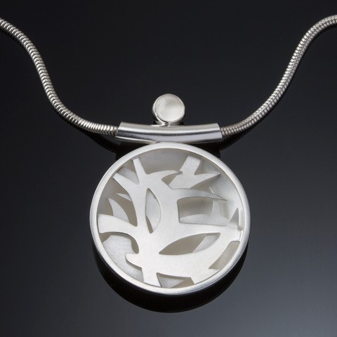 Silver circular pendant with inset abstract shapes