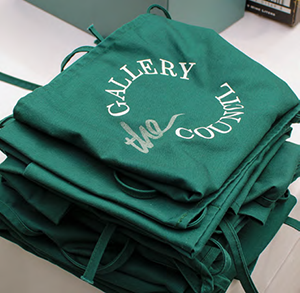 A stack of green Gallery Council aprons