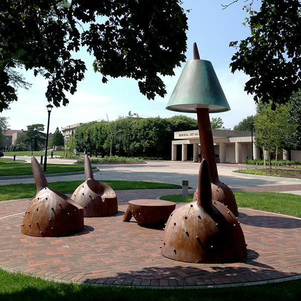 An outdoor seating area with four sculptural chairs seated around a central circular table