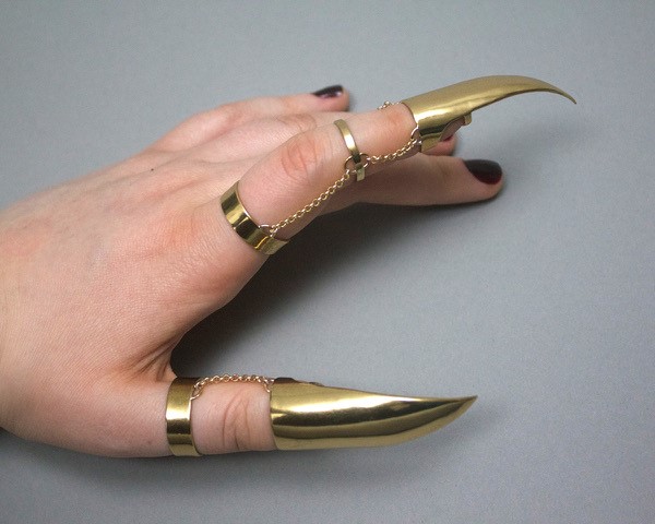 A hand wearing gold talons