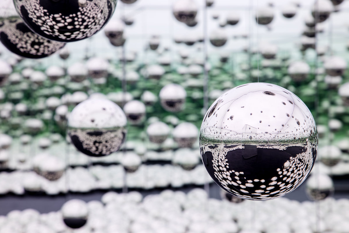 Silver, mirrored balls hanging in mid-air in a mirrored room