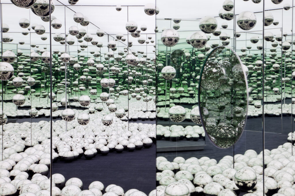Interior of a mirrored room with silver metal balls on the floor