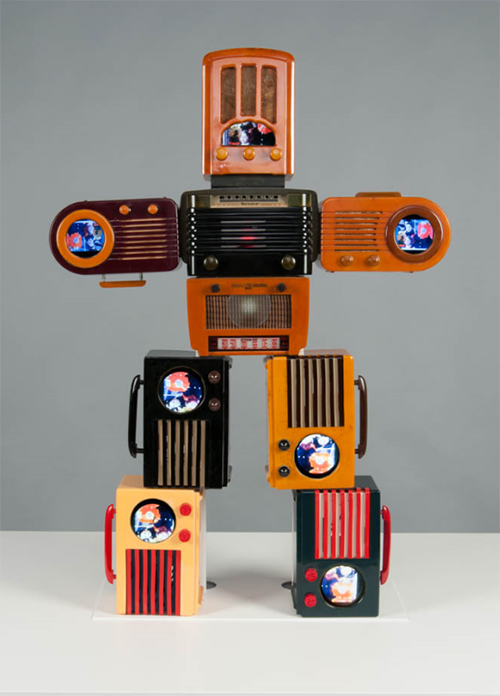 Standing robot made out of nine old-fashioned portable televisions.