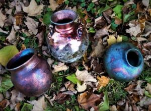Three iridescent pots sitting on leaves