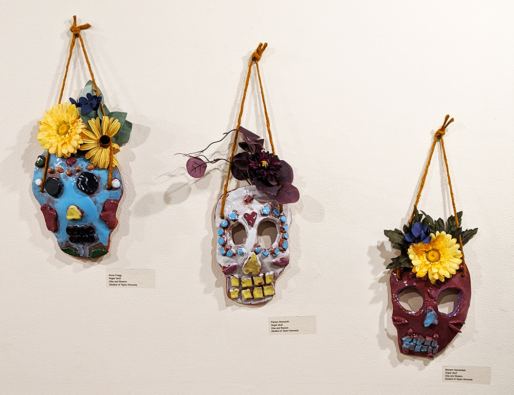 Three flat, ceramic skulls decorated with flowers hanging on a wall