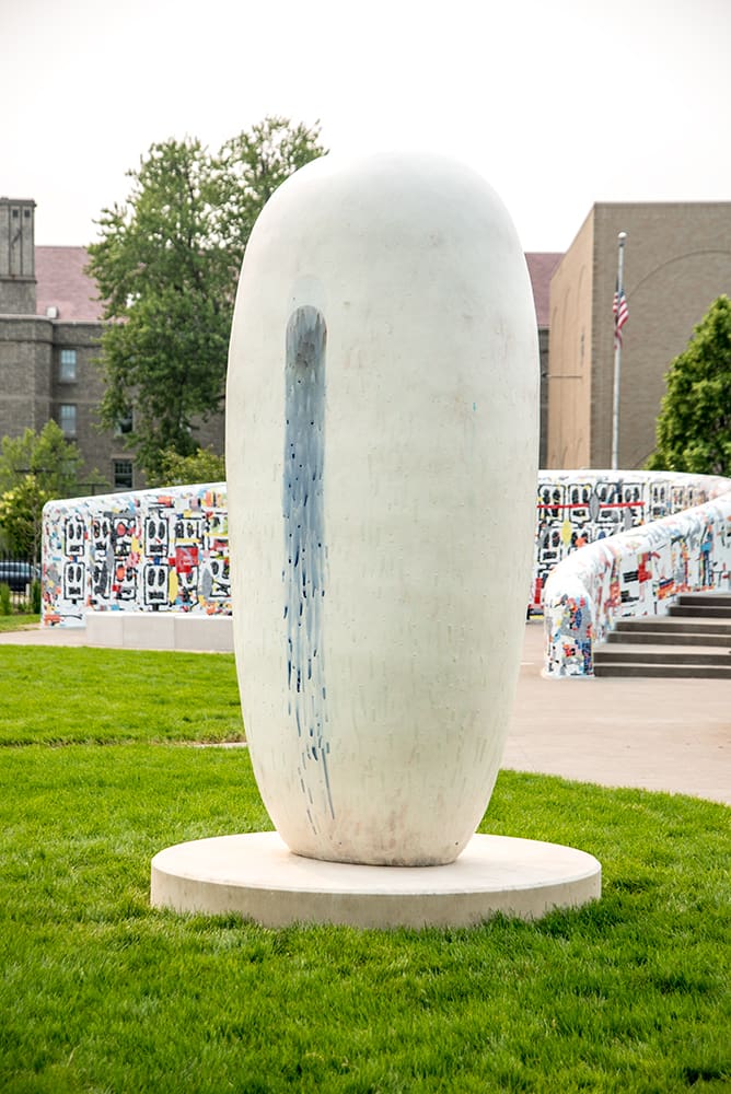 An oblong white sculpture with blue glaze trickling down the side.
