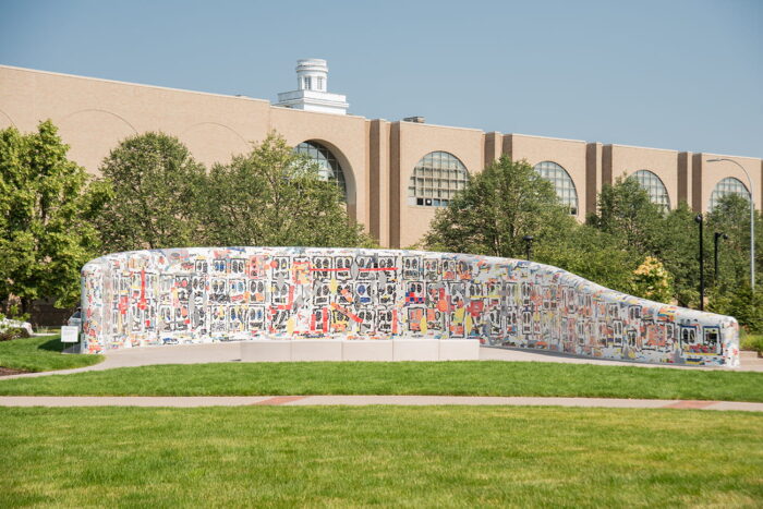 A ceramic wall covered in bright mosaic tiles curving in the form of an amphitheater.