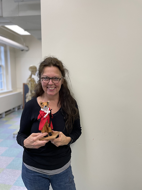 Sue Barnes holding a felted fox in a red coat.