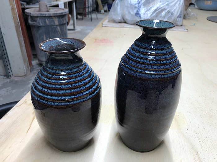 Two dark blue ceramic vases with rings at the top of the vessels.