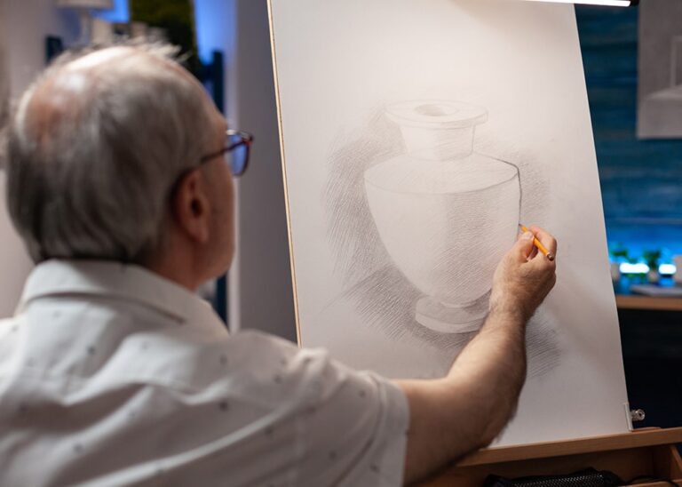 Man using a pencil to sketch an image of a vase.
