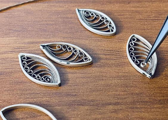Paper filligree is coiled into strands and encased in an oblong metal case.