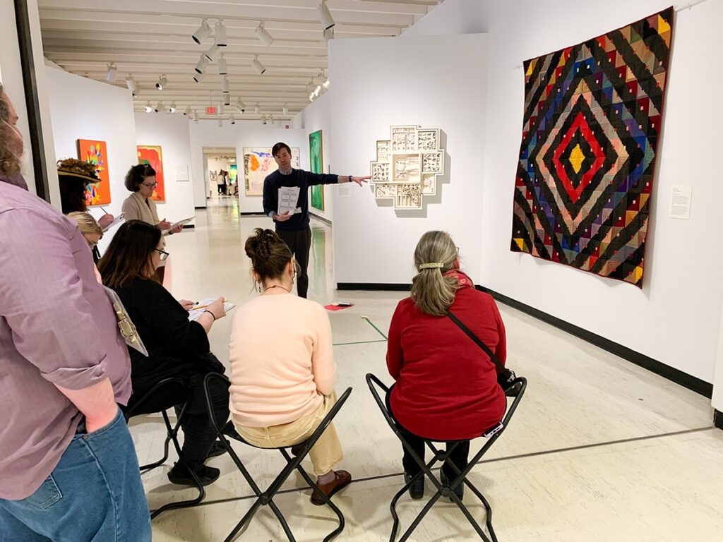 A museum educator leading a discussion with teachers in the galleries.