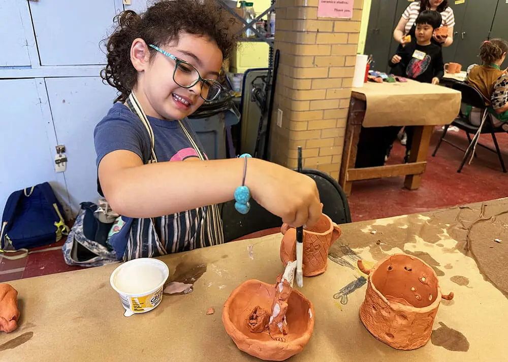 A kid glazing handmade ceramic mugs.