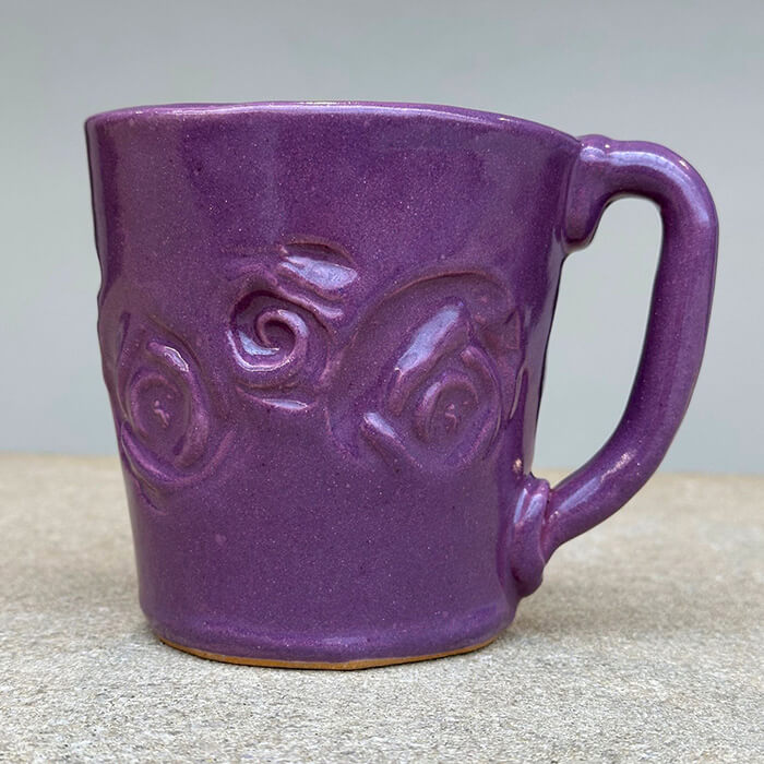 A purple, handmade ceramic mug.