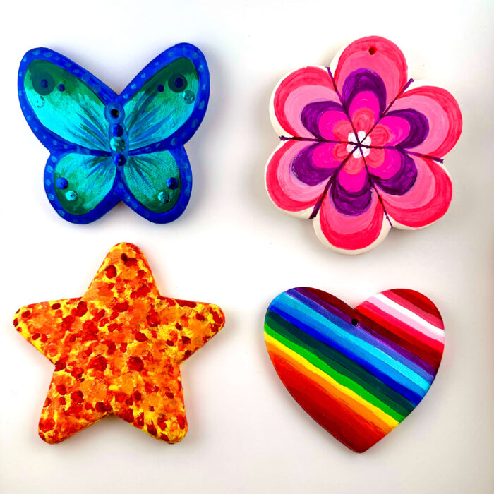 Four painted ornaments: a blue butterfly, a pink flower, an orange star, and a rainbow heart.