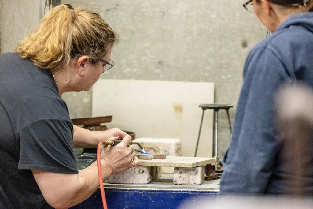 A woman using a blowtorch in the jewelry studio.