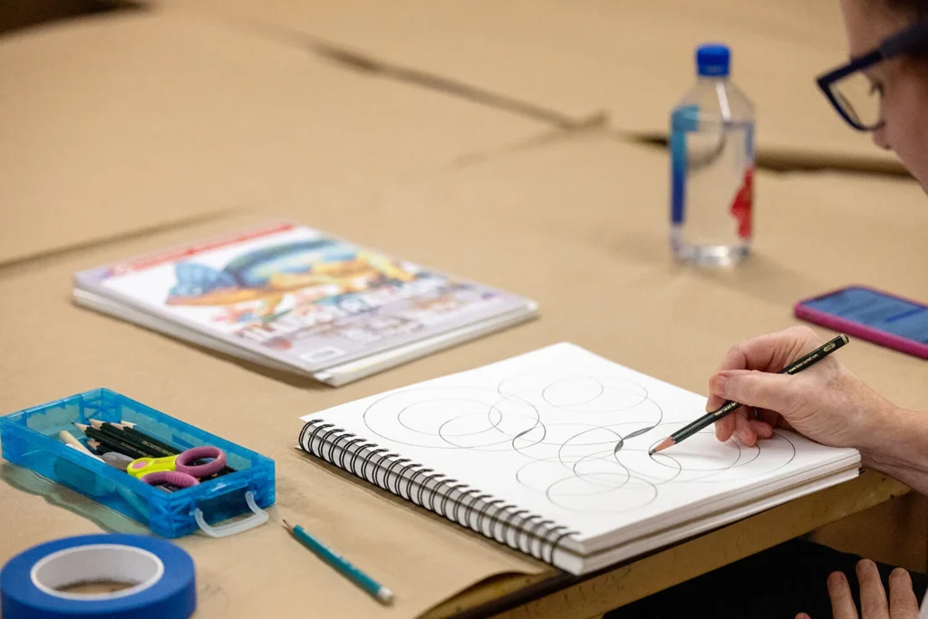A person filling in the overlapping space between different circles drawn in a sketchbook.