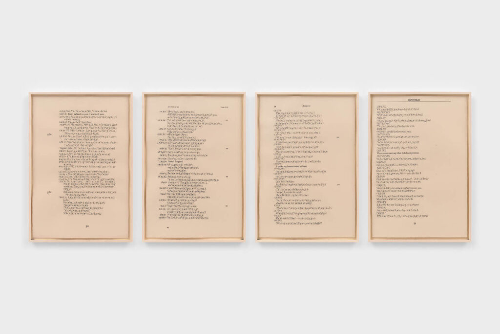 Four large, framed pieces of paper; words are written on the paper but erased so harshly that the paper is torn up, although the traces of the words are visible.