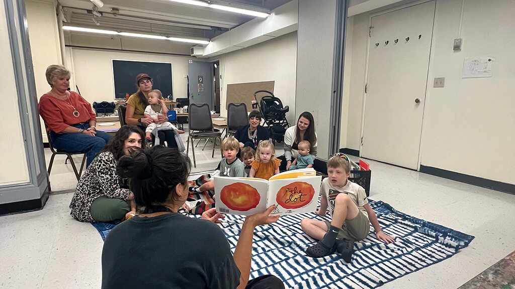 Parents and kids listen to a story in the Creative Workshop.