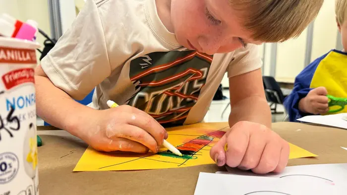 A kid drawing with markers.