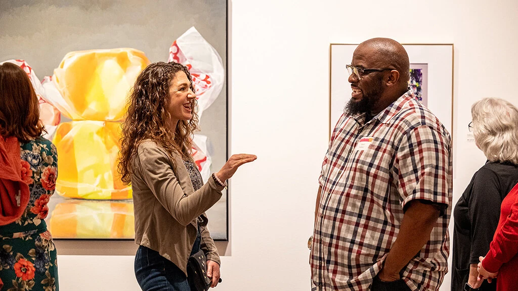 An artist and a MAG Member talking at a RFLX member opening party.