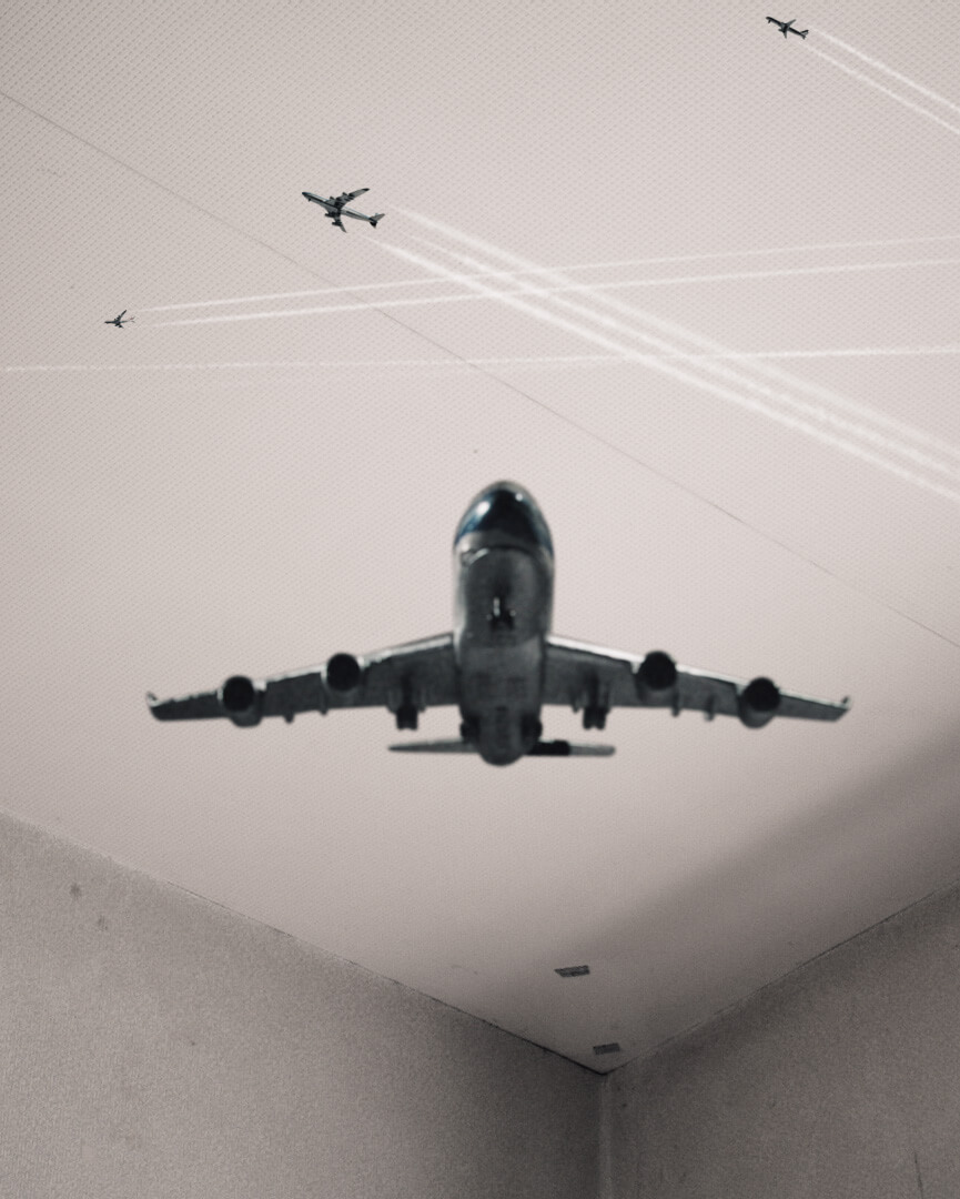Several planes appear to fly through the air in the corner of a room with blank walls.