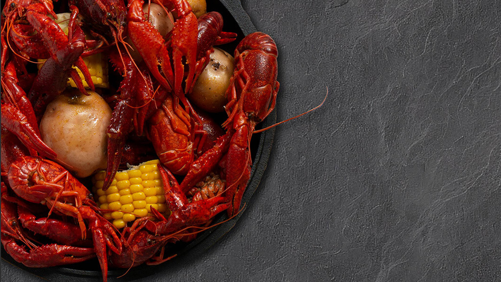A pot of boiled crawfish against a dark slate background.
