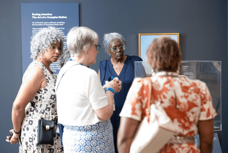 A tour guide talking with visitors in the American art galleries.