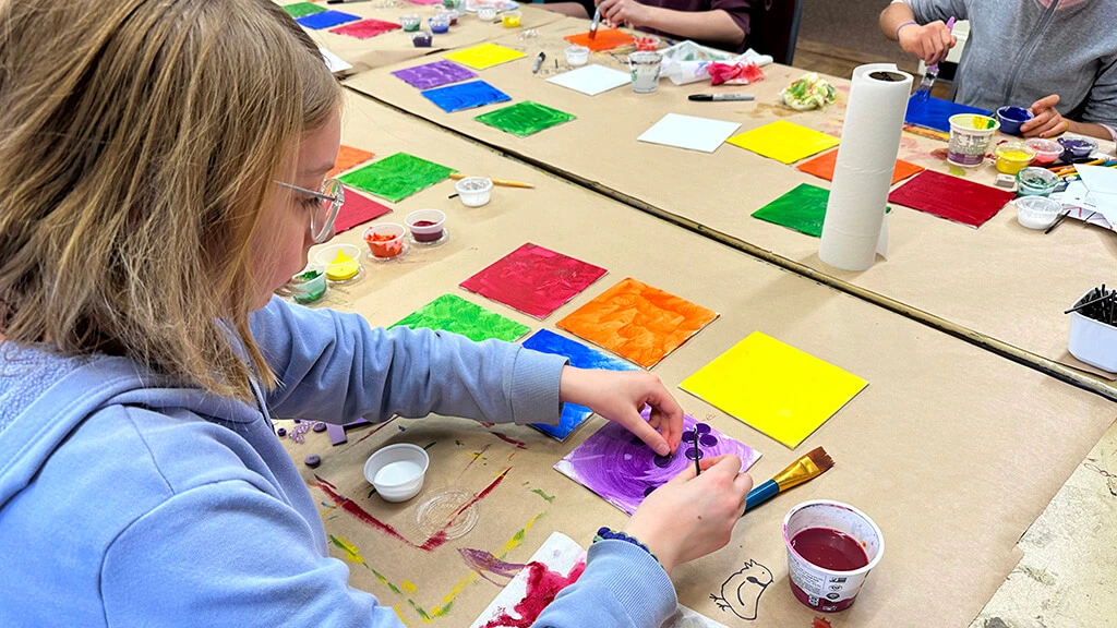 A girl works on colorful paintings in the Creative Workshop.
