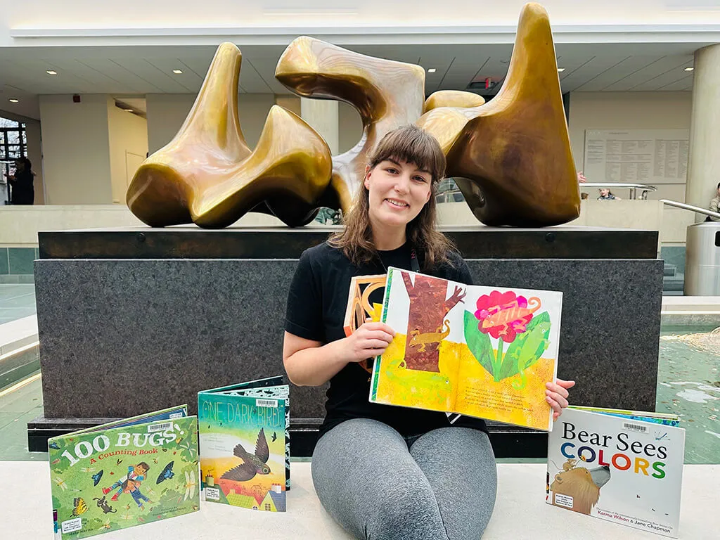 Instructor Maddie Stuart sitting in the Vanden Brul Pavilion holding picture books.