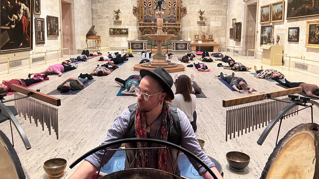 People doing yoga in MAG's Fountain Court, Harold Taddy playing music in the foreground.