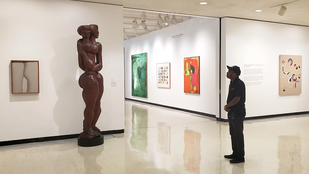 A man looking up at John Rhoden's sculpture "Generations" in MAG's contemporary art galleries.
