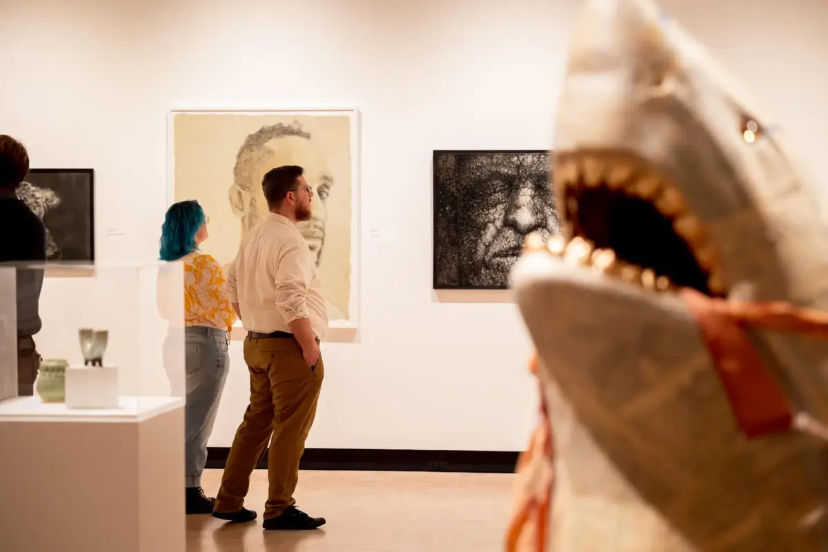 Two visitors wandering through the 69th Rochester-Finger Lakes Exhibition, a shark sculpture in the foreground.
