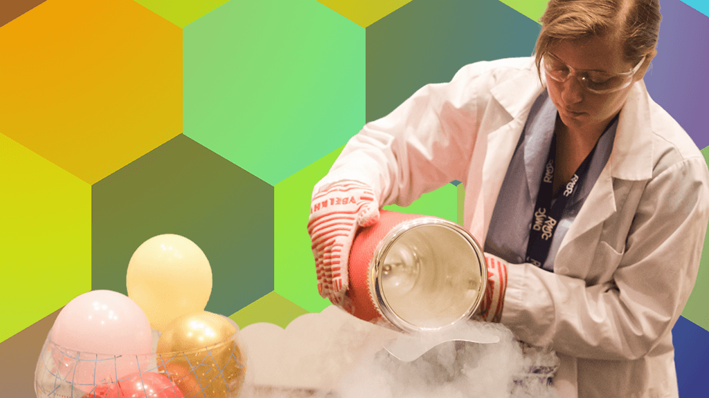 A woman in a white lab coat creates fog with liquid nitrogen.