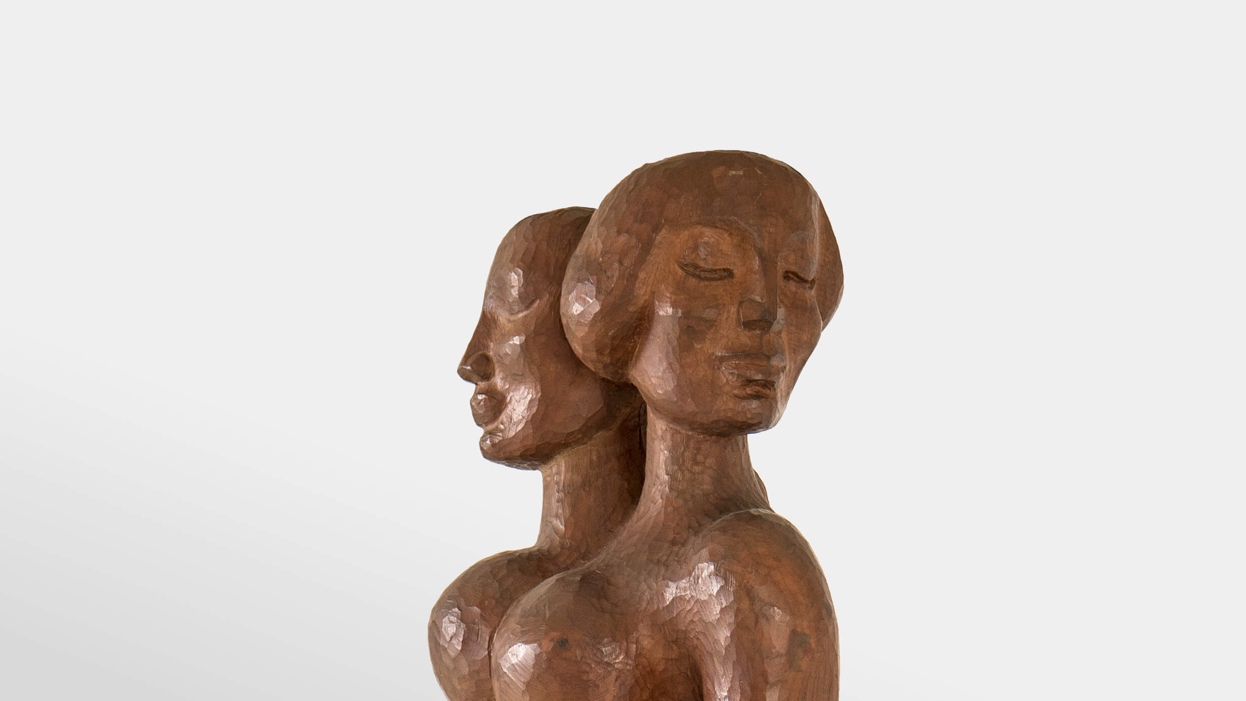 Two serene women's heads, carved out of shining wood.