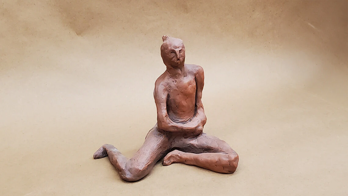 An abstract ceramic sculpture of a sitting figure.