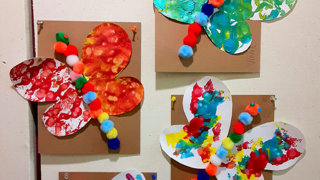 A collection of butterfly art projects created with pompom balls and paint.